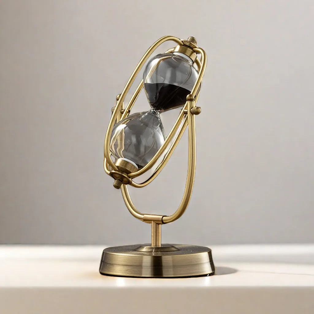 Decorative sand timer with gold frame and clear sand compartments on a neutral background