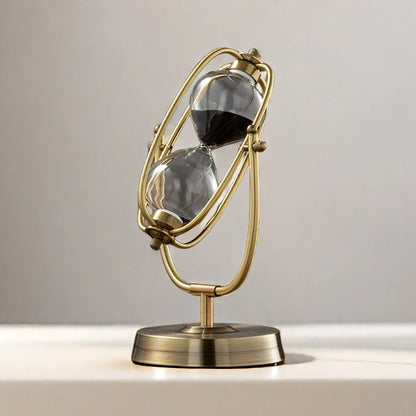 Decorative sand timer with gold frame and clear sand compartments on a neutral background