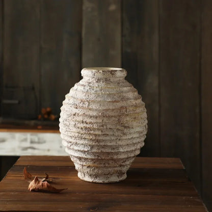 Textured ceramic vase on a wooden surface with a blurred background
