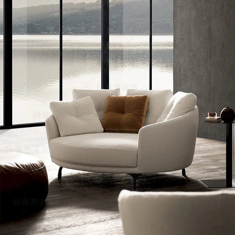 Modern living room with a white sofa and large windows overlooking a lake.