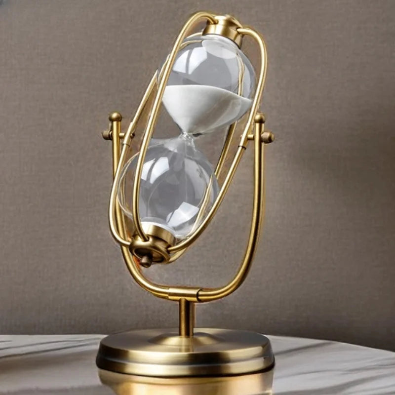 Decorative hourglass with gold frame and clear glass on a neutral background