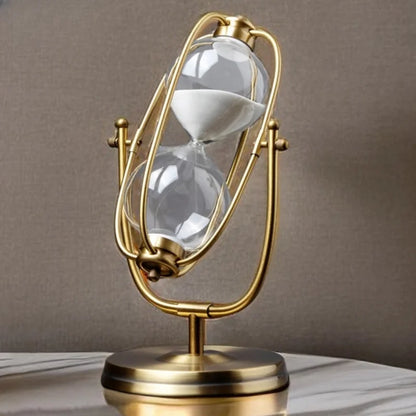 Decorative hourglass with gold frame and clear glass on a neutral background