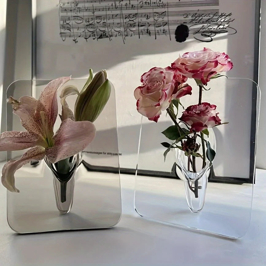 Two transparent vases with pink flowers on a white surface, with sheet music in the background.