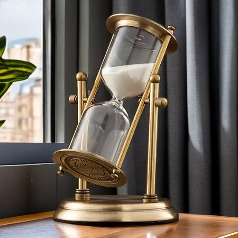 Decorative hourglass with brass frame on a table near a window