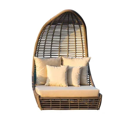 Stylish outdoor rattan sun lounger with decorative pillows.