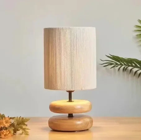 Wooden table lamp with a textured beige shade on a light wooden surface.