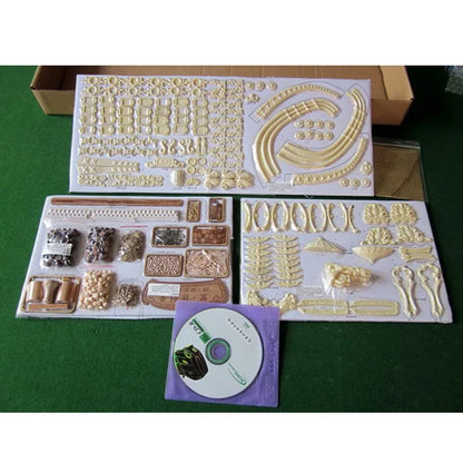 Decorative modeling kit with various pieces and a CD on a green surface