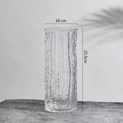 Clear glass vase with measurements on a gray surface and light gray background