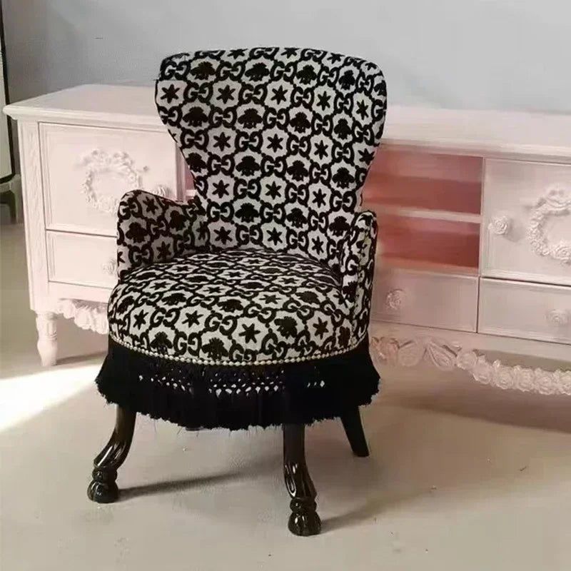 Decorative chair with black and white pattern in front of a white cabinet.