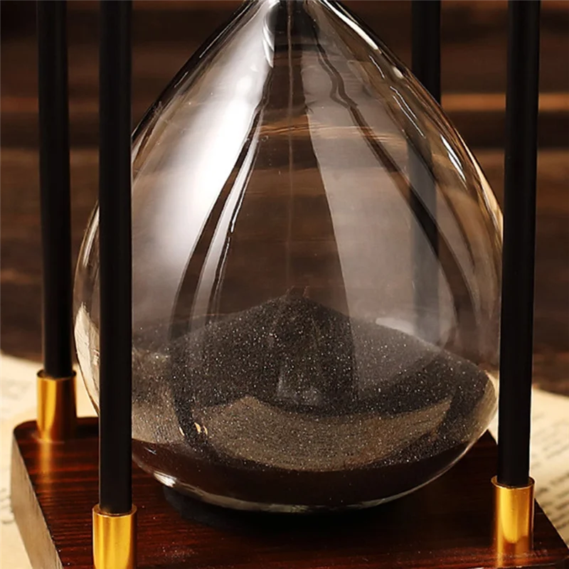 Hourglass with sand running through, placed on a wooden base.