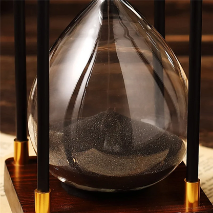 Hourglass with sand running through, placed on a wooden base.