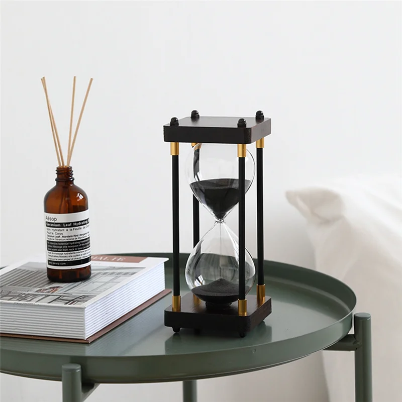 Hourglass on a round green table with a bottle and book in the background