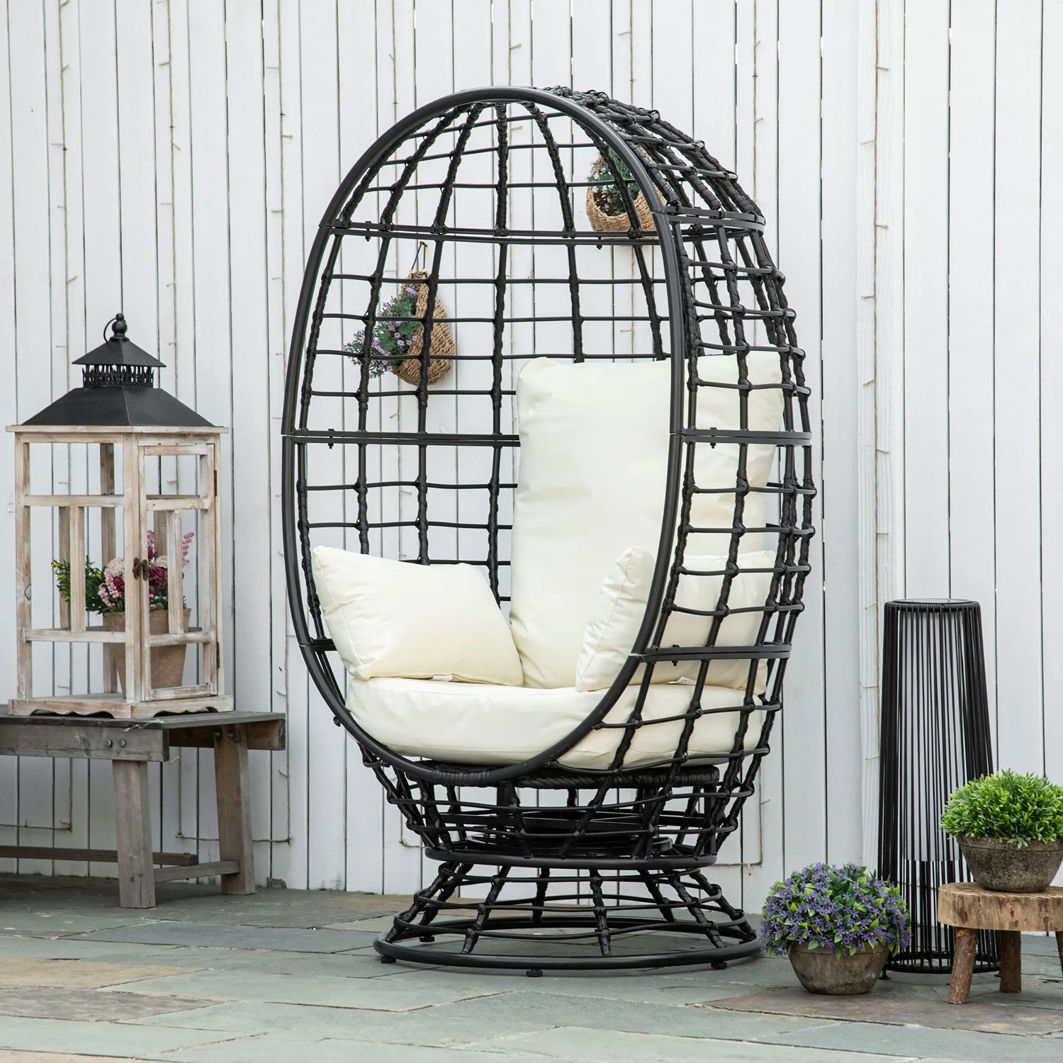 Black wicker egg-shaped chair with white cushions in an outdoor setting.