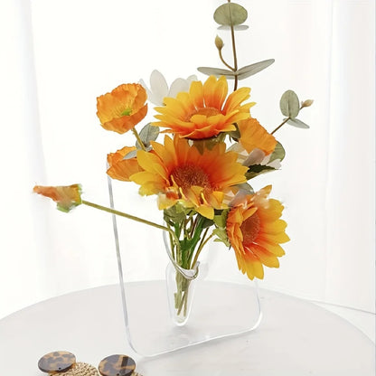 Clear glass vase with orange and yellow flowers on a white surface