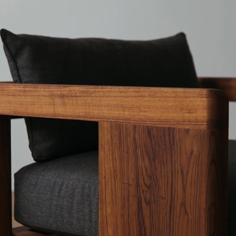 Wooden armchair with dark cushions against a neutral background