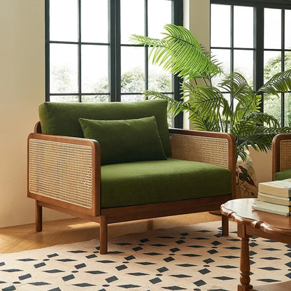 Green sofa with wicker backrest in a room with large windows and plants.