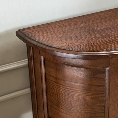 Wooden sideboard with curved top against a neutral wall