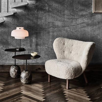 Modern interior with a textured wall, wooden floor, and a textured armchair.
