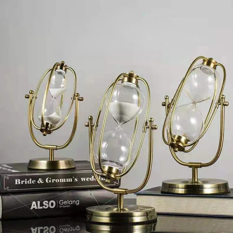 Three gold hourglass-like decorative items on books with a plain background