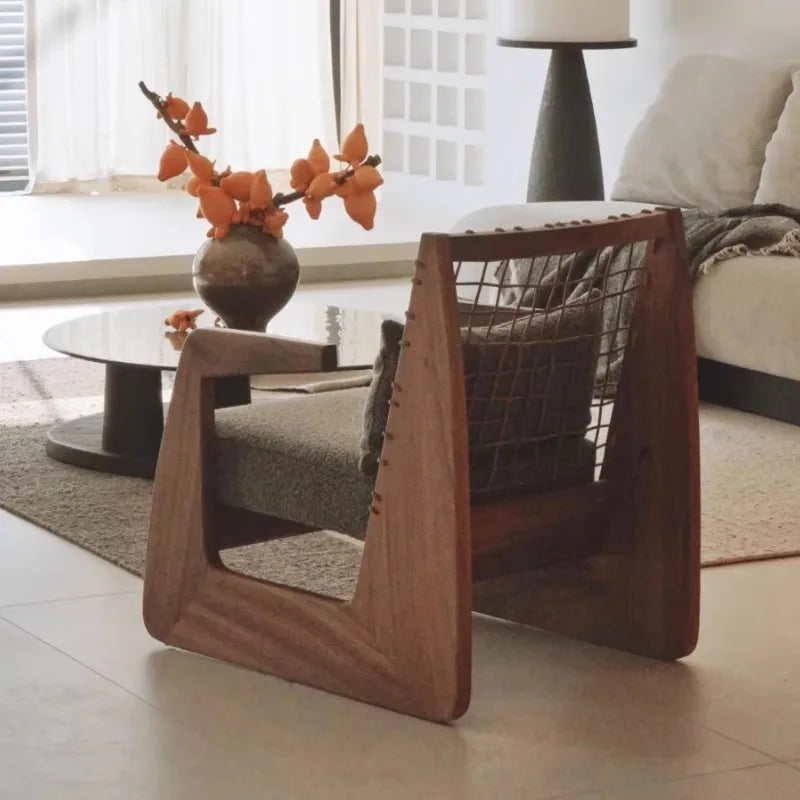 Wooden chair in a living room setting with a vase of flowers and a lamp in the background.