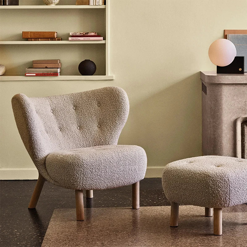 Gray textured armchair and ottoman in a room with a shelf and lamp.