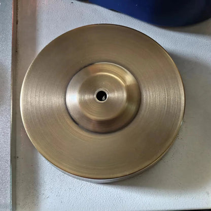 Gold-colored metal disc on a light gray surface