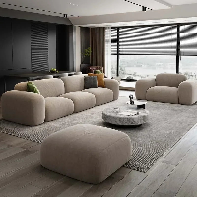 Modern living room with beige sofa, ottoman, and coffee table.