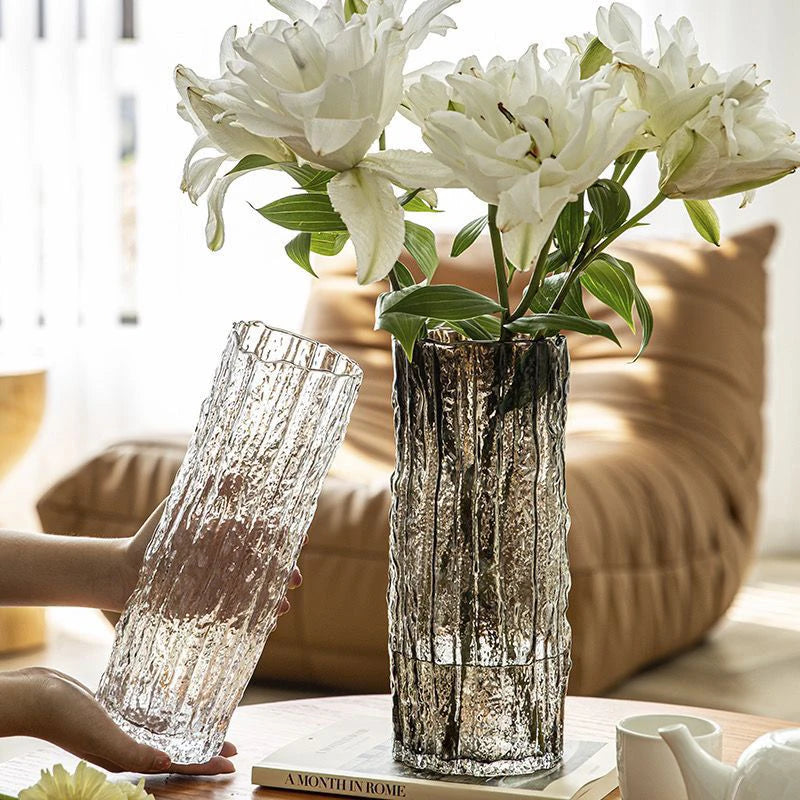 Two decorative vases with white flowers on a table in a living room setting.