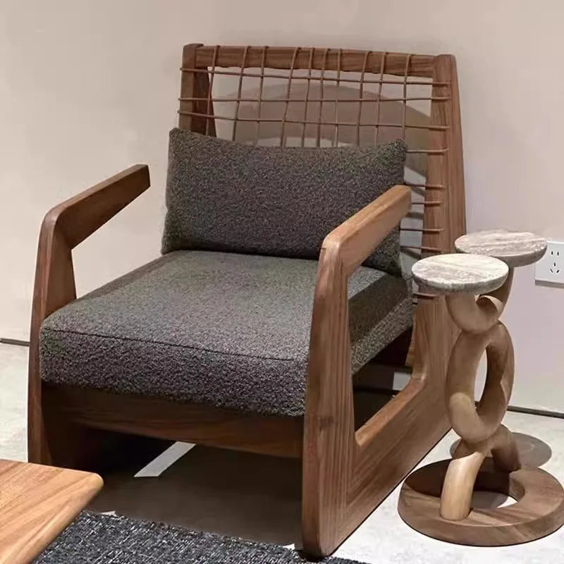 Wooden armchair with gray cushion and small wooden stool in a room setting.