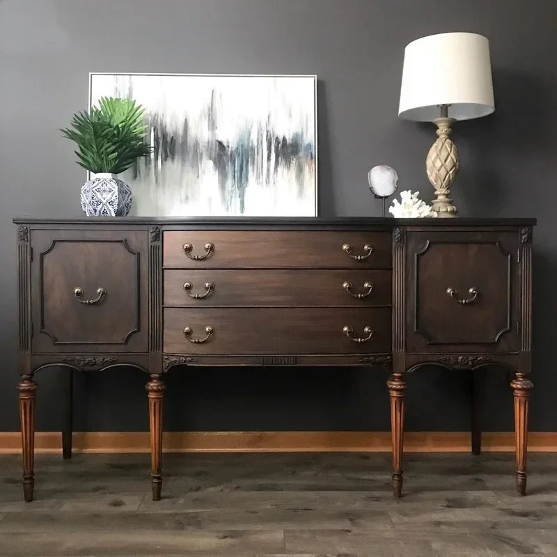 Wooden sideboard with decorative items against a dark wall
