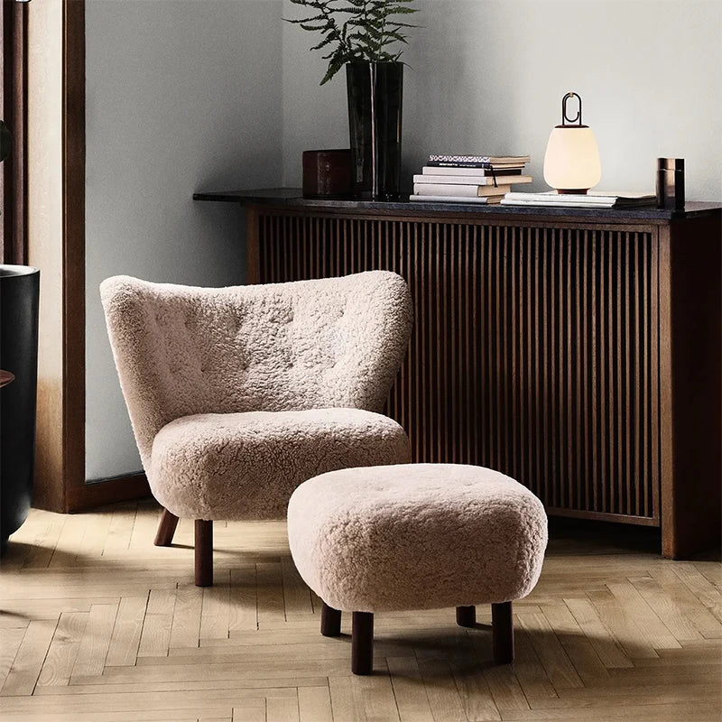 Beige textured armchair and ottoman in a room with wooden floor and sideboard.