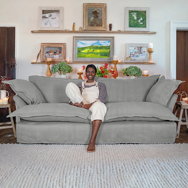 Person sitting on a gray sofa in a living room with framed pictures on the wall.