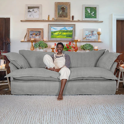 Person sitting on a gray sofa in a living room with framed pictures on the wall.