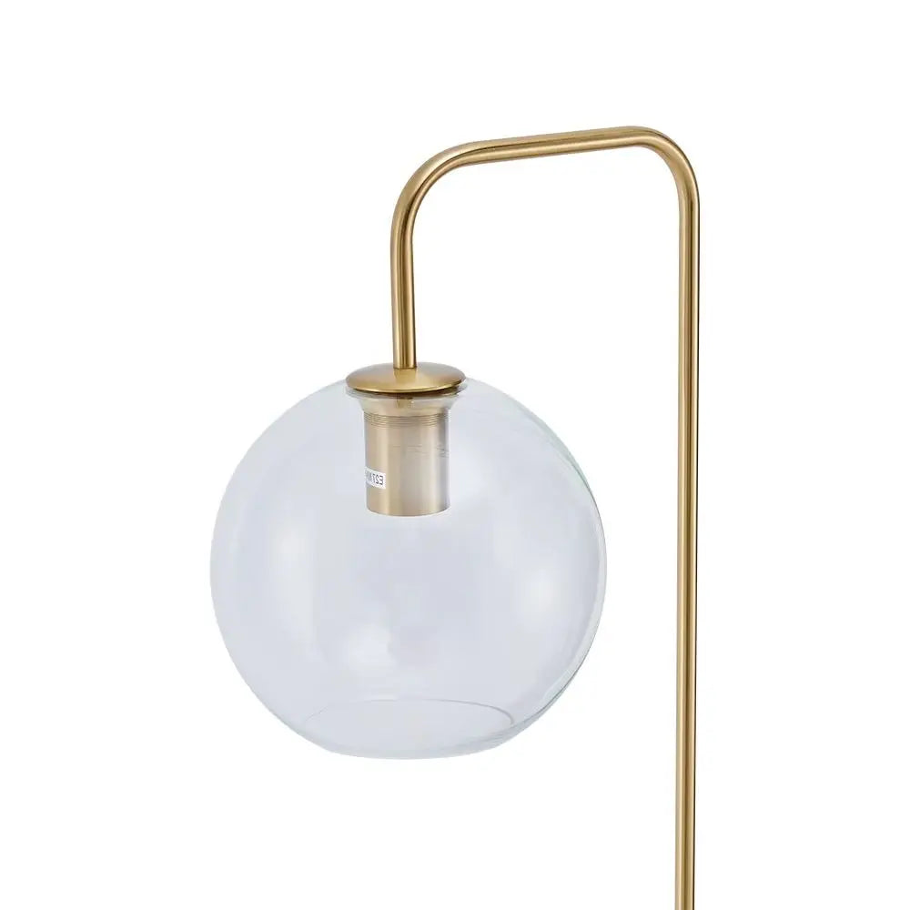 Modern table lamp with a gold base and white glass shade on a white background