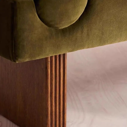 Close-up of a green upholstered headboard with wooden legs on a bed.