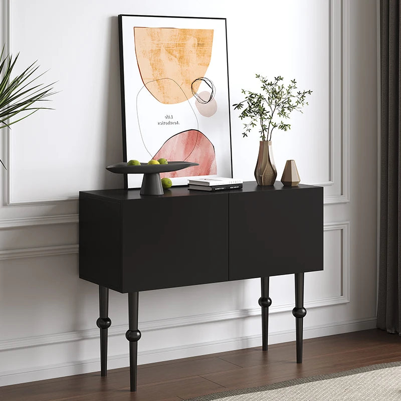 Black console table with decorative items against a white wall with abstract art.