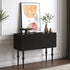 Black console table with decorative items against a white wall with abstract art.