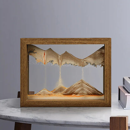 Wooden frame with sand art depicting mountains on a marble surface.