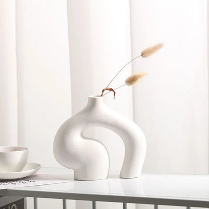 White ceramic vase with a unique design on a white surface with a minimal background