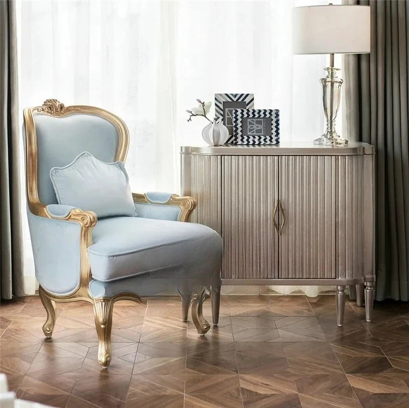 Luxury armchair with gold accents in a stylish room with a sideboard and lamp.