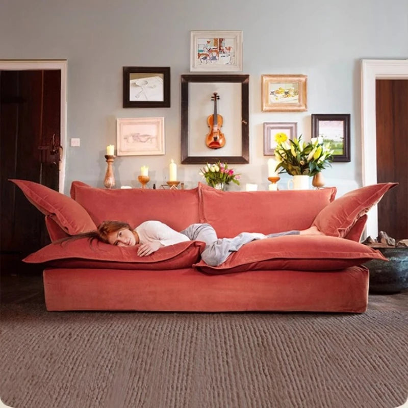 Person lying on a large red sofa in a living room with decorative elements.