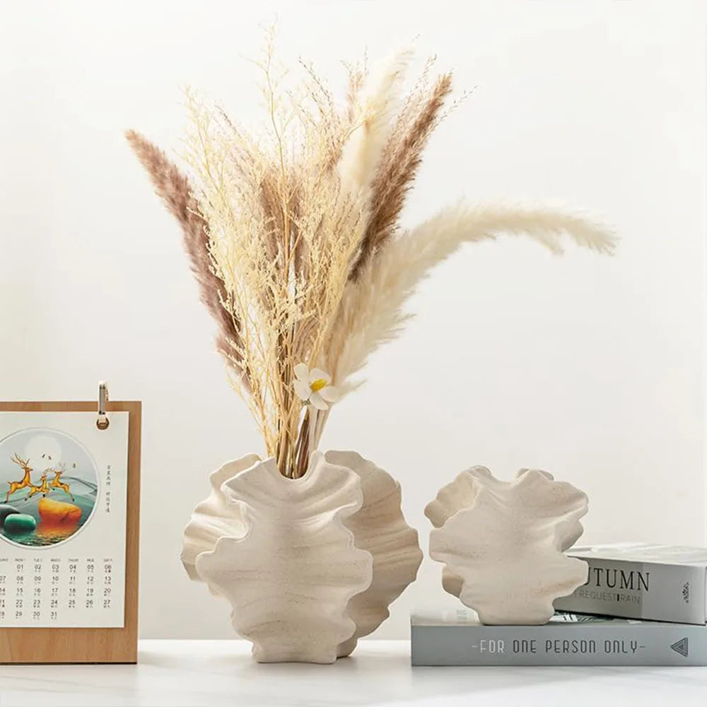Decorative vases with dried plants on a white surface