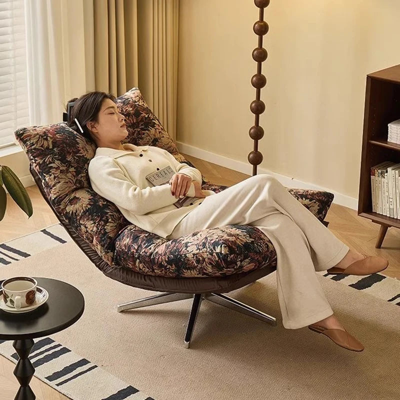 Woman relaxing on a floral-patterned chair in a cozy living room.