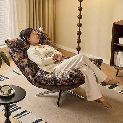 Woman relaxing on a floral-patterned chair in a cozy living room.