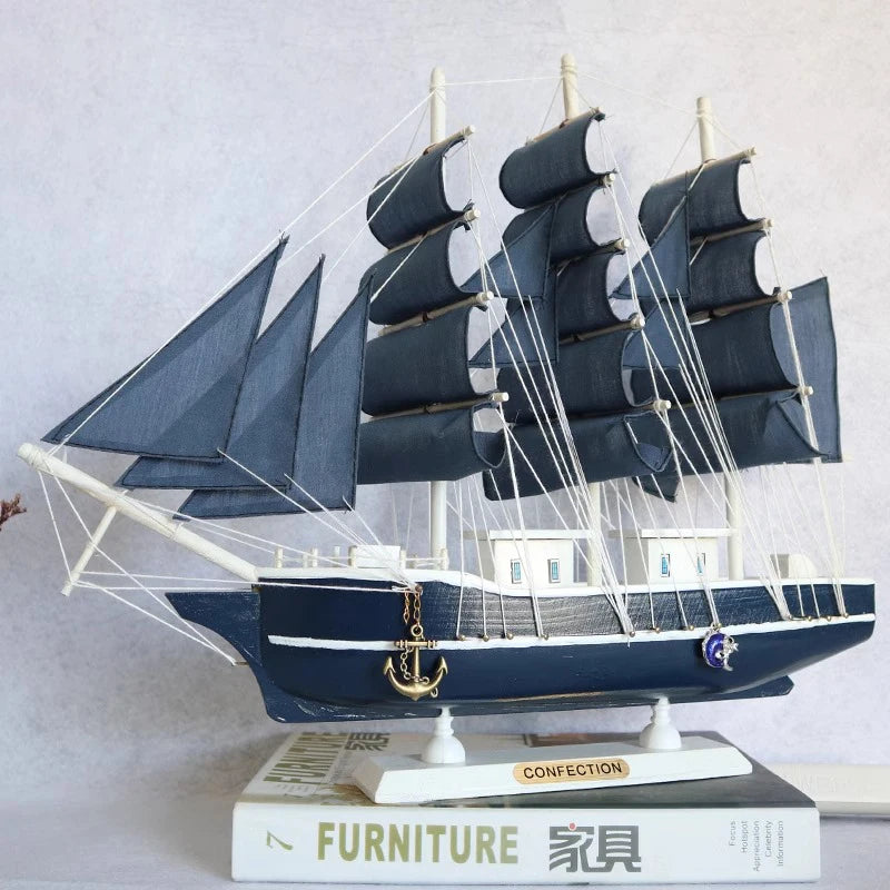 Model ship with dark blue sails on a white surface