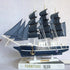 Model ship with dark blue sails on a white surface
