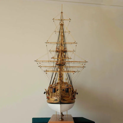 Model of a tall ship on a stand against a plain wall