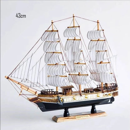 Model sailboat with multiple sails on a light gray background