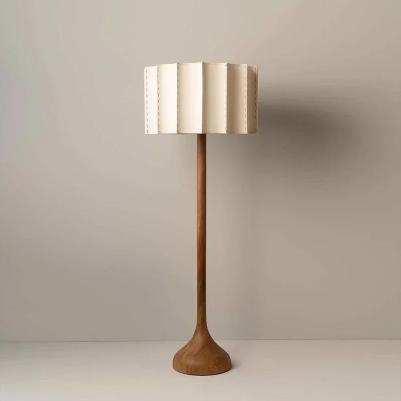 Tall floor lamp with a wooden base and metallic shade on a plain background