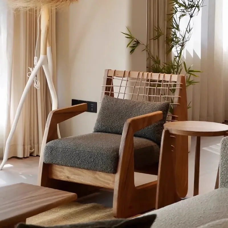 Wooden armchair with gray cushions in a room with curtains and a plant.